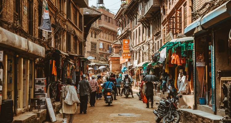 Drukke straat met verkopers en motorfietsen in een culturele omgeving.
