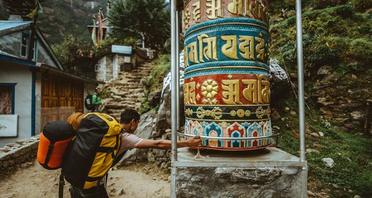 Reiziger die een groot gebedswiel met kleurrijke patronen draait.