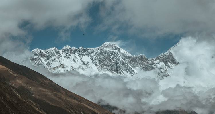 Sneeuwbedekte bergtoppen gedeeltelijk bedekt door wolken.