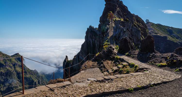 Bergpad dat leidt naar een rotsachtig uitkijkpunt omringd door wolken