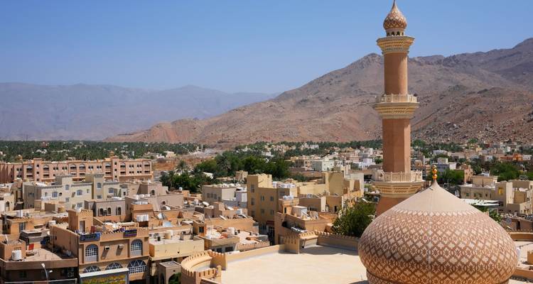 Een moskee met een grote koepel in een woestijnstadslandschap.