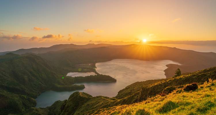 Een gloeiende zonsondergang werpt goudkleurig licht over de Sete Cidades caldera en meren op het eiland São Miguel.