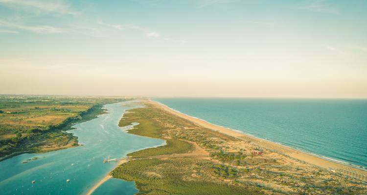 Long sandbar and lagoon meeting the Atlantic under a pastel sunset sky.