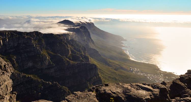 Dramatic Table Mountain cliffs rising above clouds and the Atlantic Ocean at sunset light