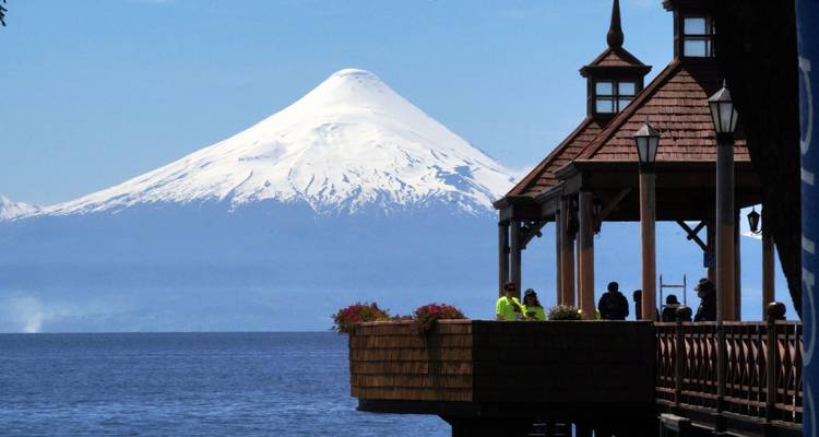 Volcan enneigé avec une jetée en bois au-dessus d'un lac.