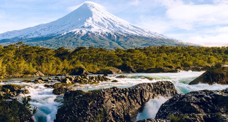 Montagne enneigée avec une forêt et une rivière tumultueuse.