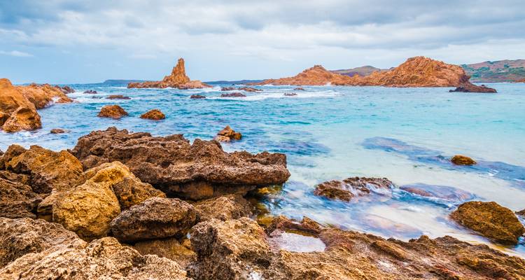 Rivage rocheux avec des eaux azur et de petits îlots.