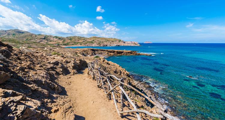 Un sentier de randonnée côtier avec une clôture en bois surplombant la mer.