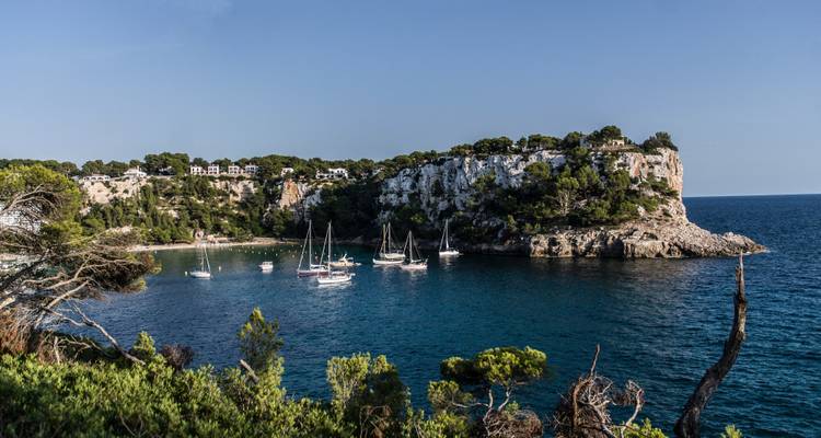 Une crique avec des bateaux à l'ancre entourée de falaises.