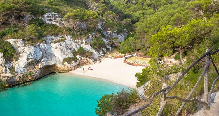 Secluded beach with turquoise water and green cliffs.