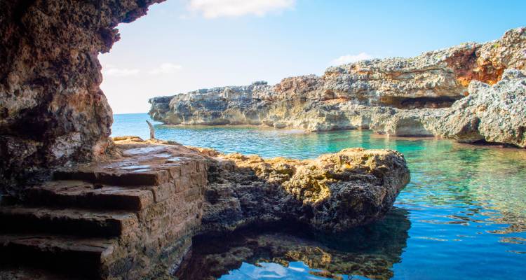 Coastal cave entrance with clear blue water views.