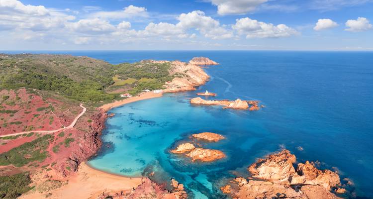 Vista aérea panorámica de una costa de arenisca roja y aguas azules.