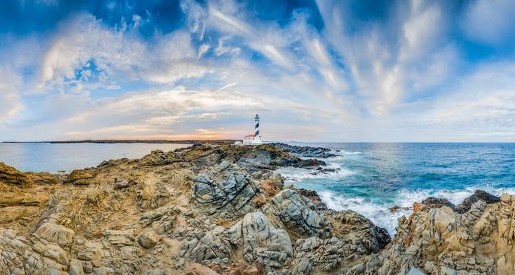 Panoramic view of a rugged coastline with a lighthouse.