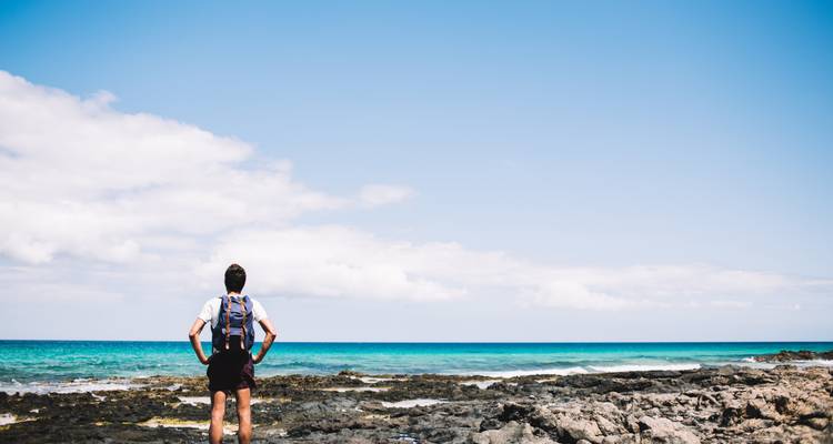 Person standing on a rocky shore looking out to the sea.