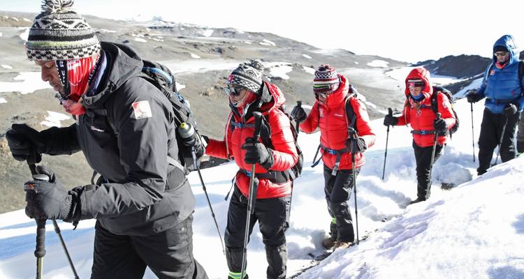 Randonneurs en équipement d'hiver marchant sur un sentier enneigé.
