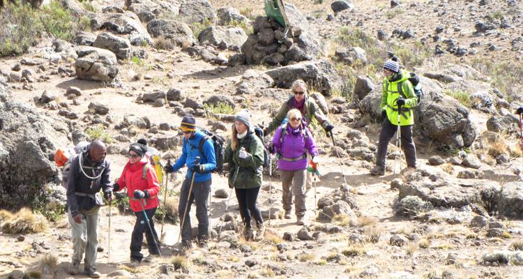Randonneurs marchant le long d'un sentier entouré d'un terrain rocheux.