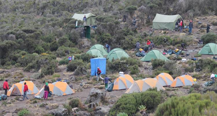 Un camping avec des tentes installées au milieu d'un terrain rocheux.