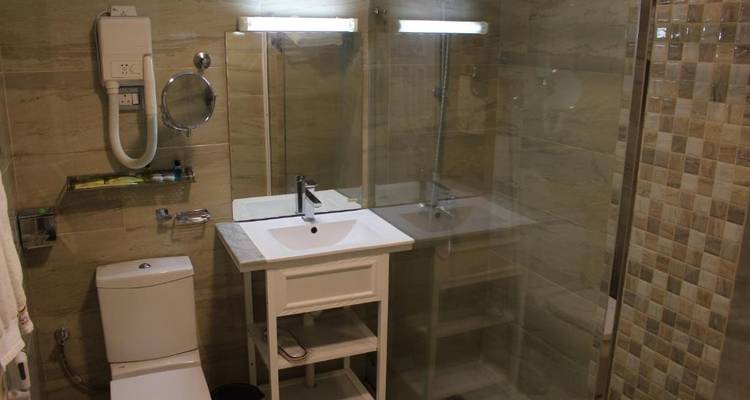 Baño moderno con ducha de cristal, lavabo y paredes con azulejos.