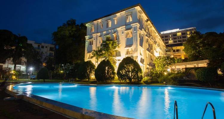 Hotelbuitenkant met zwembad verlicht 's nachts.