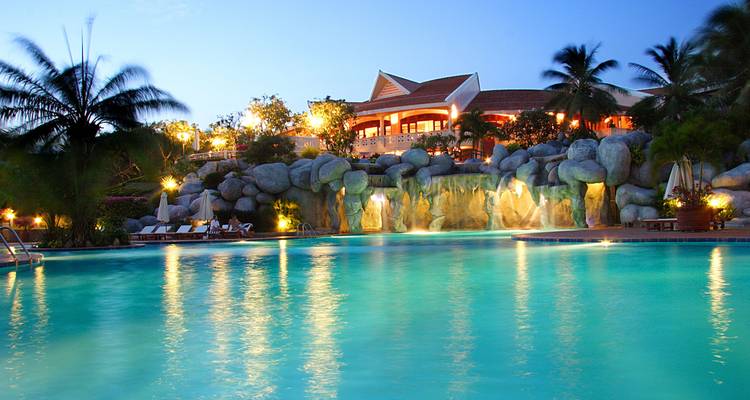 Resort mit Schwimmbad und Palmen in der Abenddämmerung.