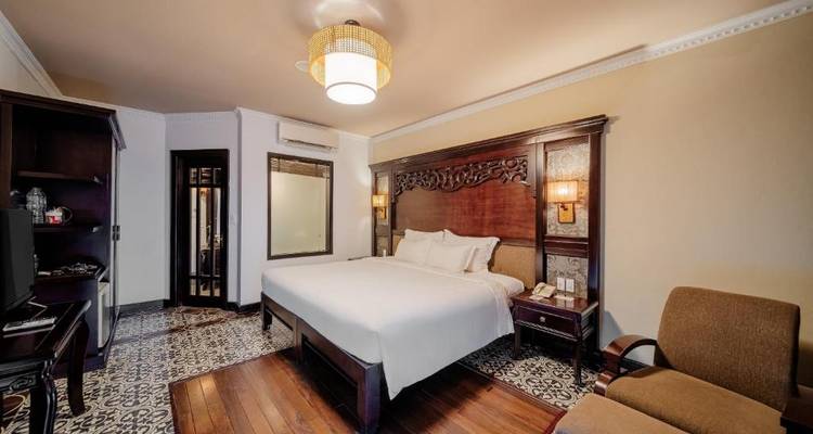 Elegantes Zimmer mit einem großen Bett und klassischer Einrichtung.