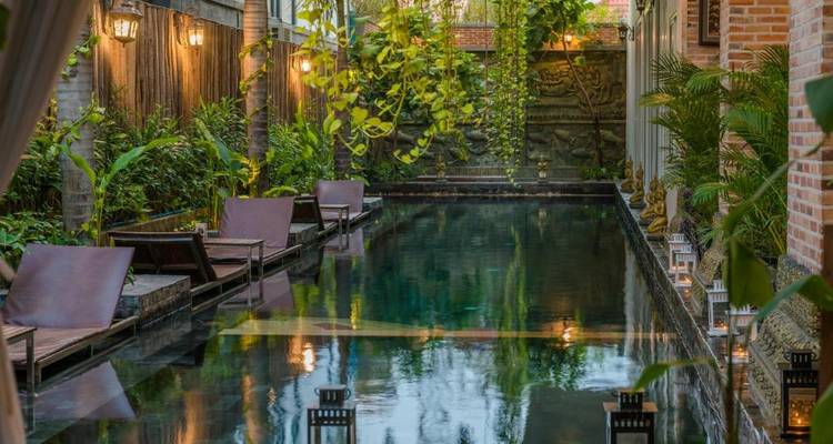 Elegant pool area with lounge chairs and lush vegetation.