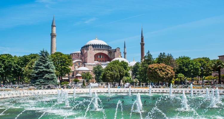 Iconische Hagia Sophia omlijst door een levendige fontein in een zonnig parklandschap.