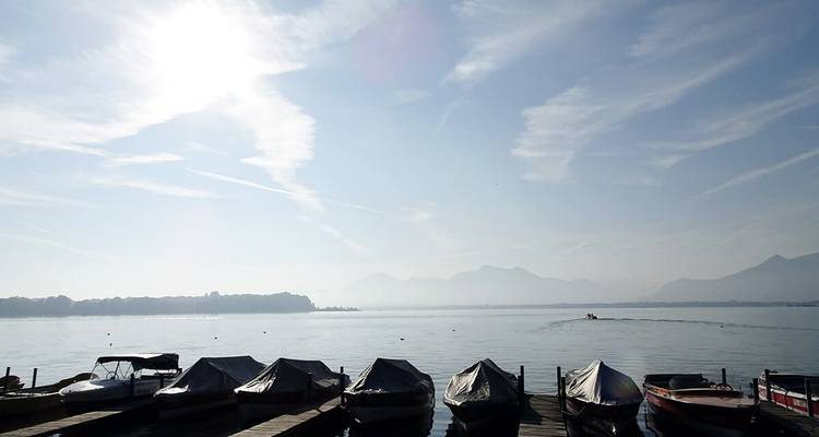 Des bateaux couverts amarrés sur un lac avec des montagnes au loin.