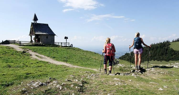 Excursionistas cerca de una pequeña capilla en la cima de una montaña.