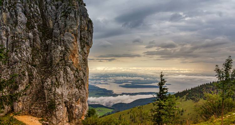 Una vista panorámica desde una montaña sobre un valle y un lago distante.