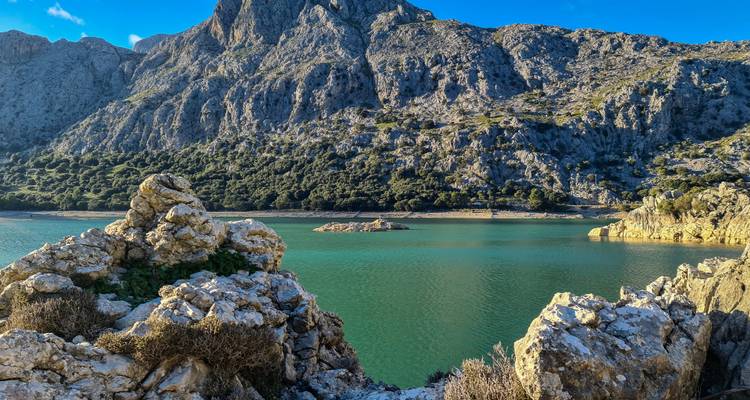 Emerald green lake surrounded by rocky cliffs and lush foliage.