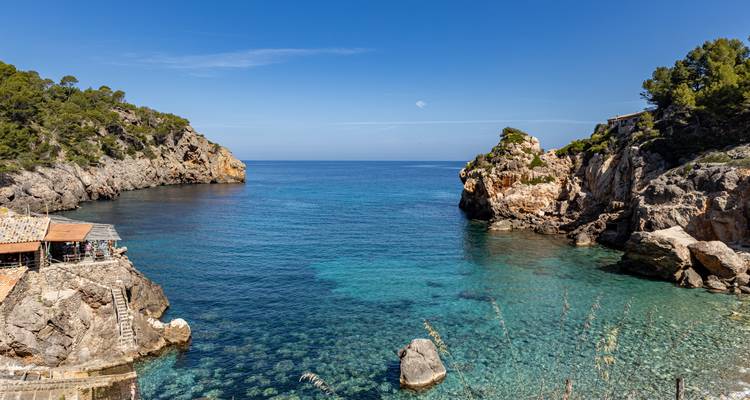 Tranquil bay with clear water surrounded by rocky cliffs.