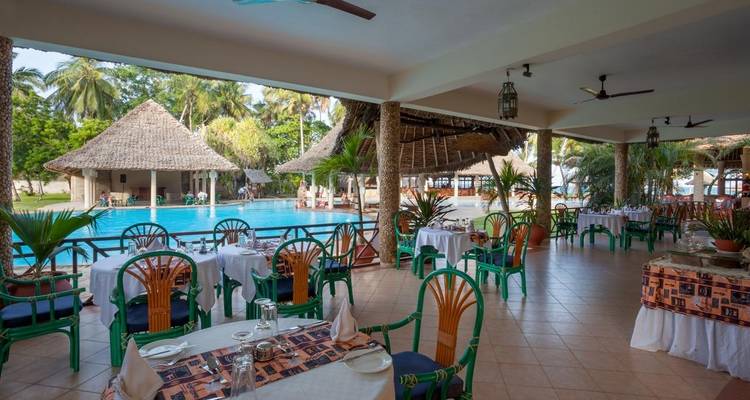 Resort restaurant with pool and tropical palm trees.