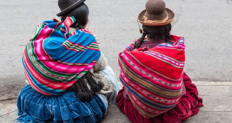 Zwei Personen sitzen und tragen traditionelle bunte Kleidung.