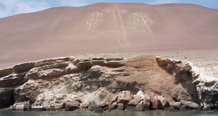 Glyf geëtst in woestijnheuvel boven rotsachtige kustlijn.