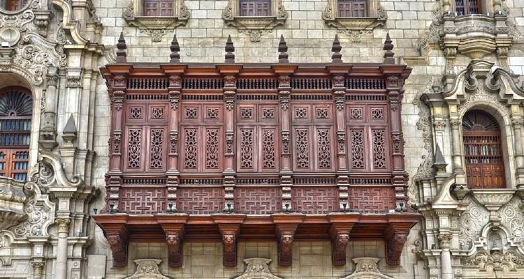 Sierlijke houten balkon op een historisch stenen gebouw.