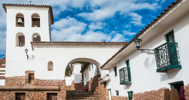 Witte stenen koloniale kerk met een booggang en blauwe lucht.