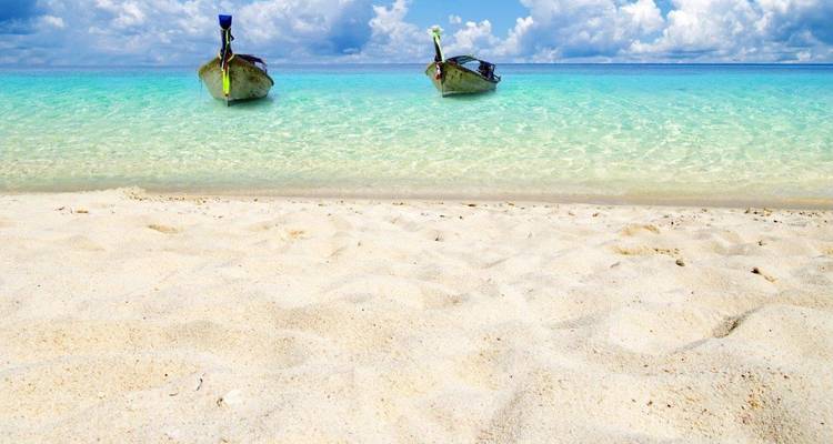Dos botes de cola larga en agua clara y poco profunda con una playa de arena.