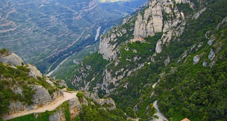 Falaises rocheuses et sentiers sinueux avec vue panoramique sur la vallée.