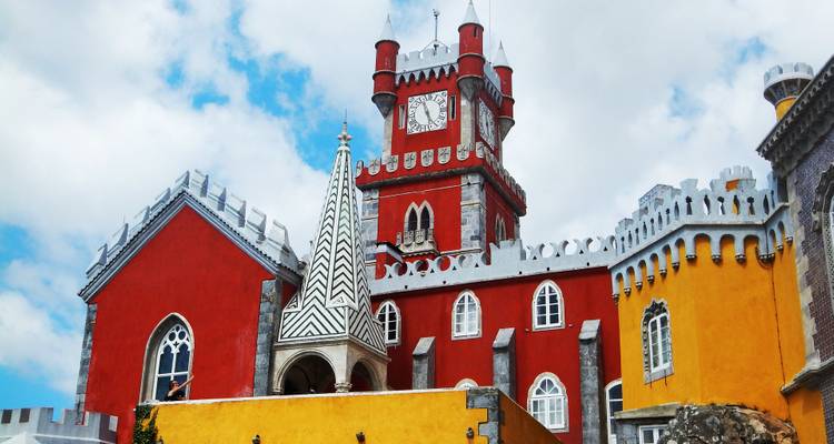 Detaillierte Architektur eines bunten Schlosses vor einem teilweise bewölkten Himmel.