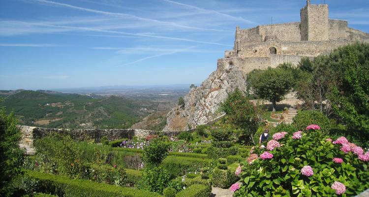 Garden with colorful flowers at a historic fortress overlooking a vast landscape.