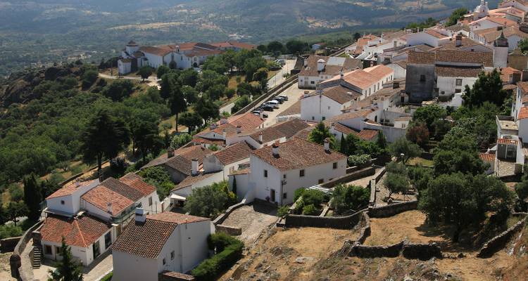 Aerial view of a village with white buildings and surrounding hills.