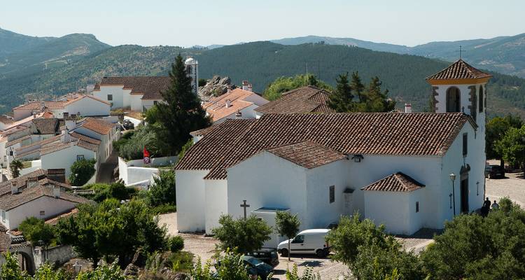 Village with a historic church surrounded by mountains.