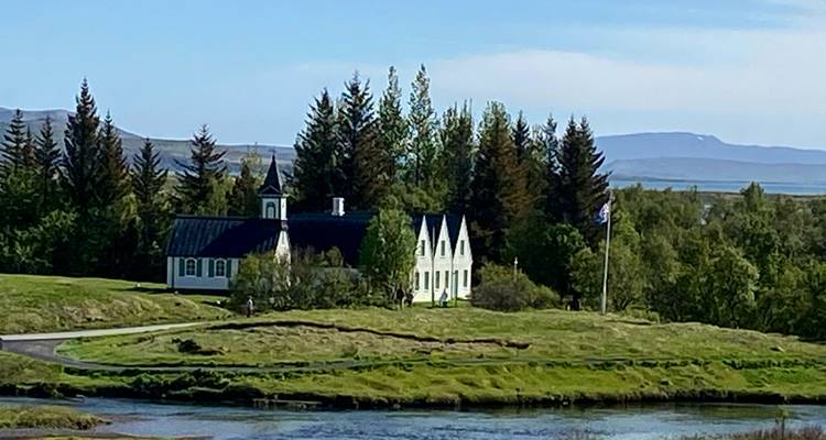 Scenic landscape with a church and trees by a river.