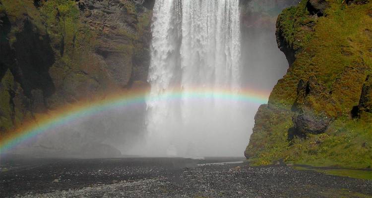 Skogafoss waterfall with a vibrant rainbow at its base.