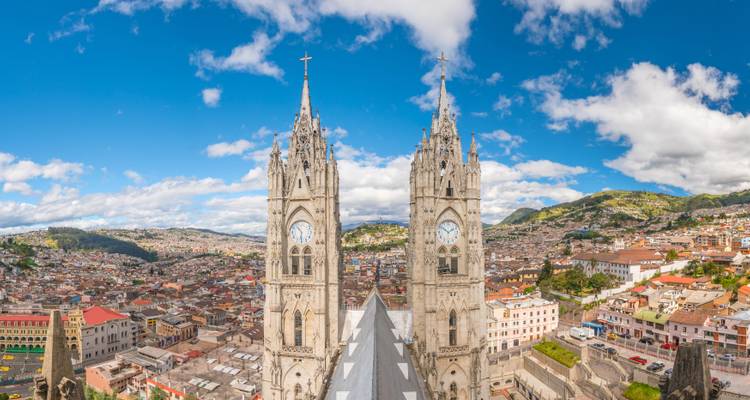 Vue panoramique de Quito avec les tours d'églises emblématiques et un arrière-plan montagneux.