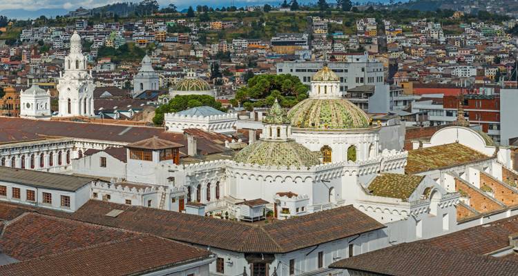 Vue panoramique des toits et églises de Quito avec les collines en arrière-plan.