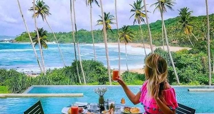 Person, die eine malerische Aussicht über einen Strand und Palmen genießt
