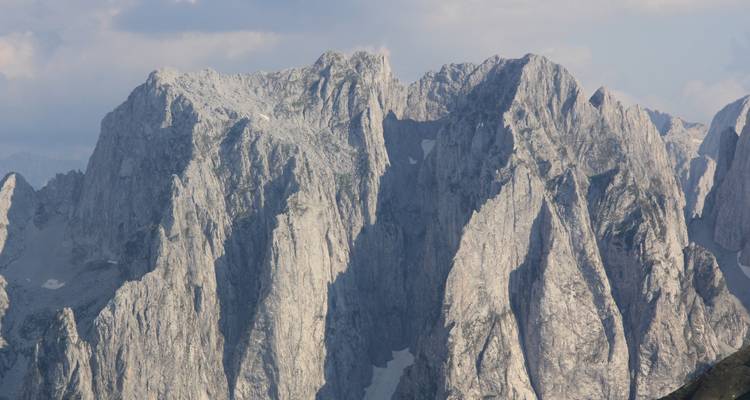 Hauts sommets rocheux sous un ciel nuageux.