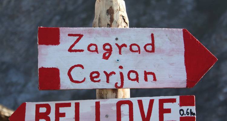 Poteau indicateur peint à la main avec destinations et flèches.